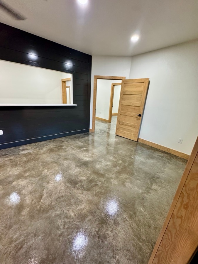 Stained and sealed concrete floor beside a black shiplap wall