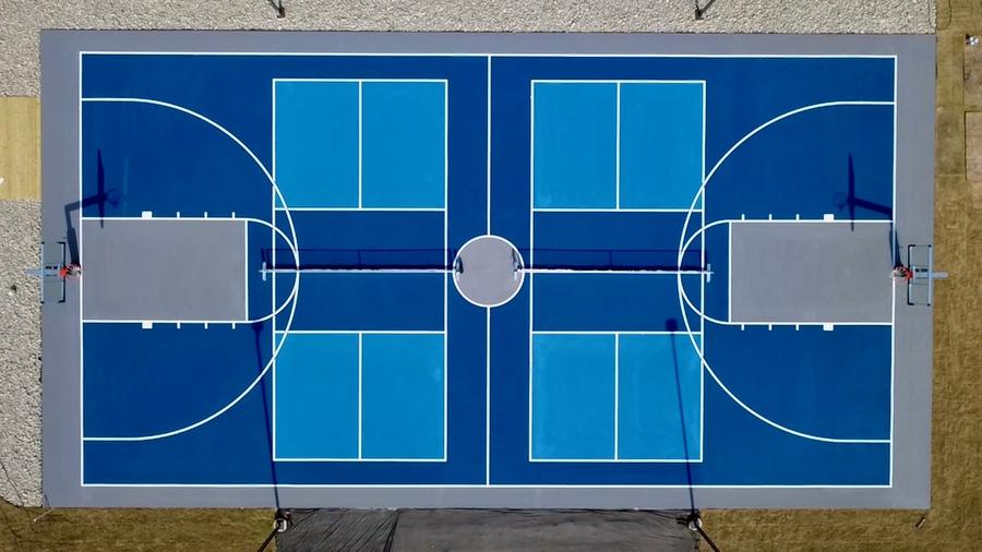 Overhead view of a blue combo court with two pickleball courts and basketball hoops at each end